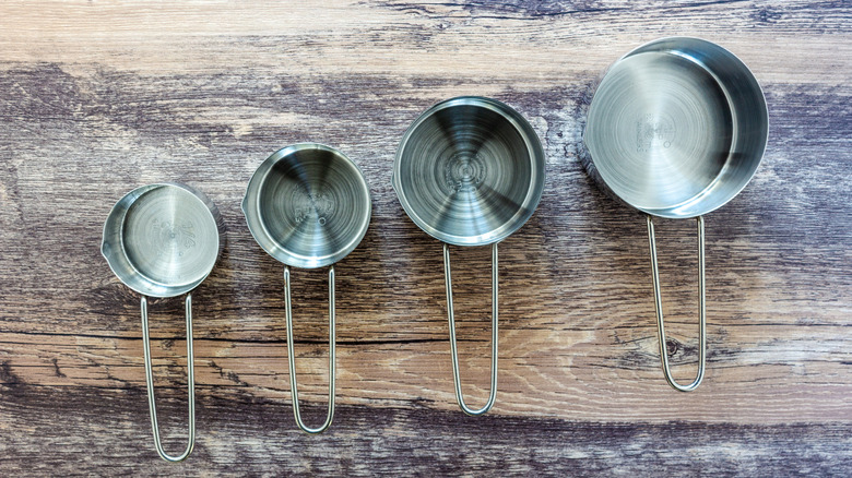 Overhead view of metal measuring cups on wooden table