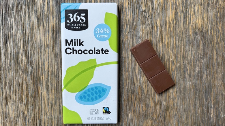 Wrapped 365 milk chocolate bar on table with long rectangular piece adjacent, consisting of three sections