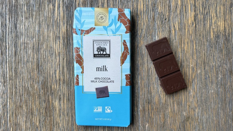 Wrapped Endangered Species milk chocolate bar on table with rectangular piece adjacent, each section adorned with elephant impression