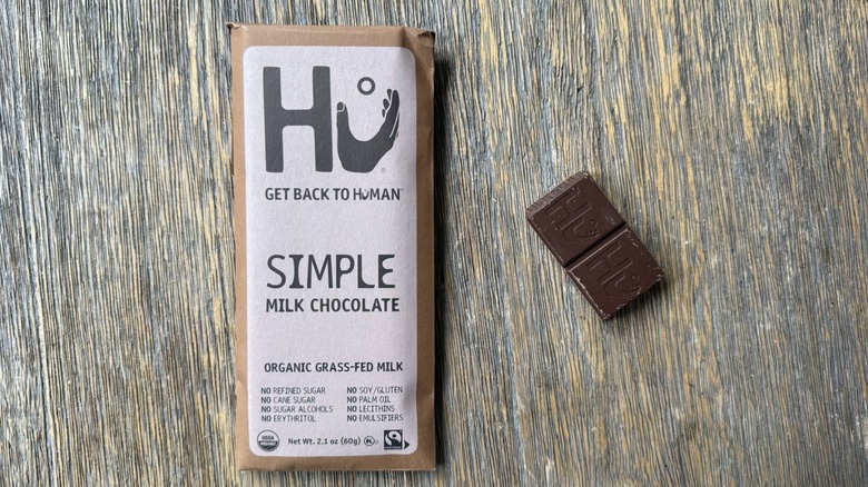 Wrapped Hu milk chocolate bar on table with rectangular piece adjacent, consisting of two sections