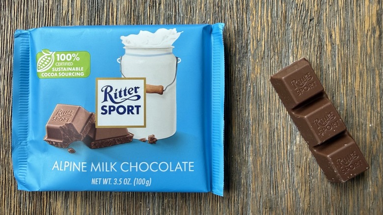 Wrapped Ritter Sport milk chocolate bar on table with rectangular piece consisting of three squares adjacent