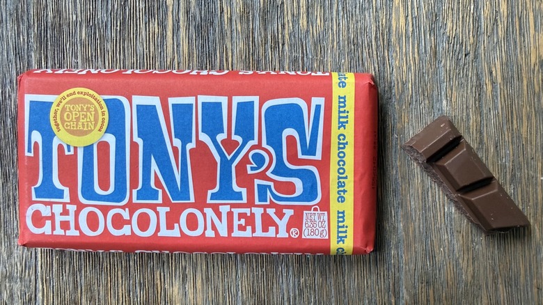Wrapped Tony's Chocolonely milk chocolate bar on table with rectangular piece adjacent