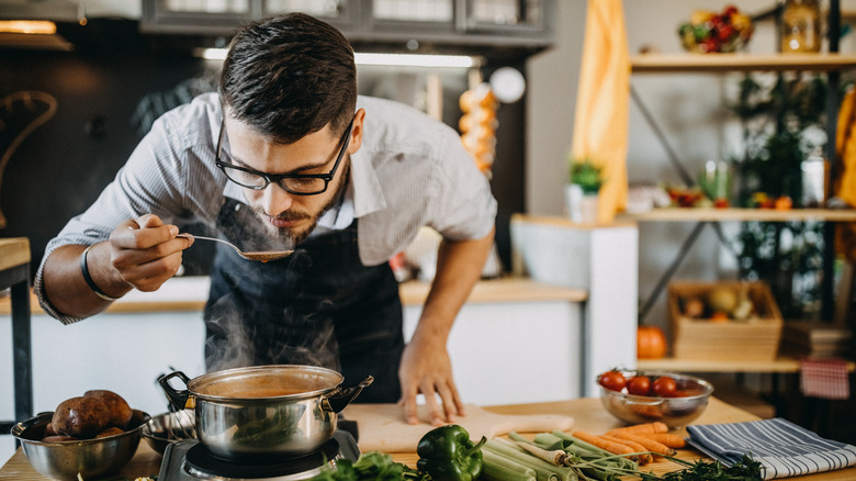 Man tasting food as he cooks in the kitchen