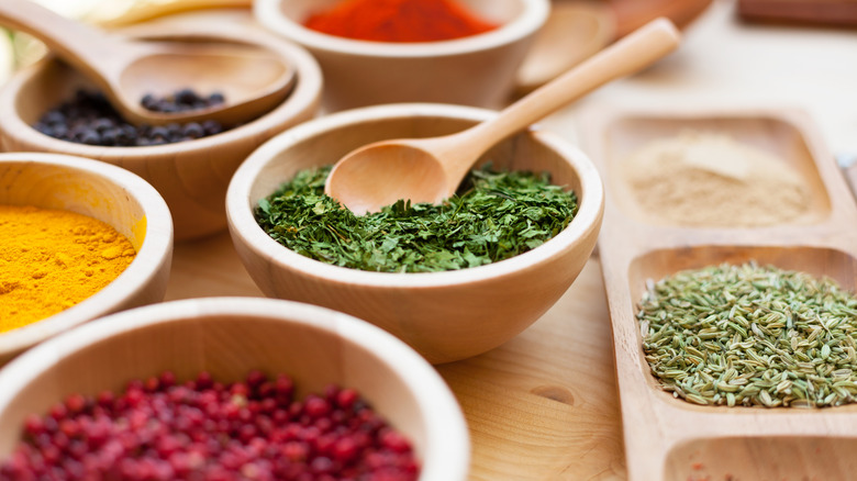 Various herbs and spices in separate wooden bowls