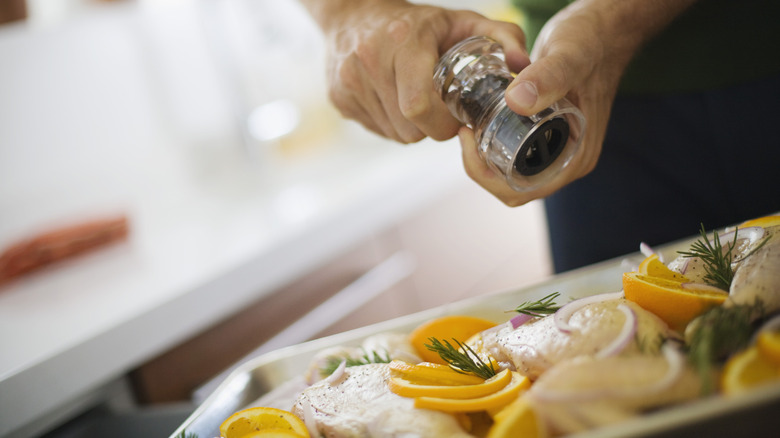 Person grinding black pepper onto dish