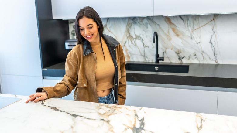 Woman touching marble countertop in showroom