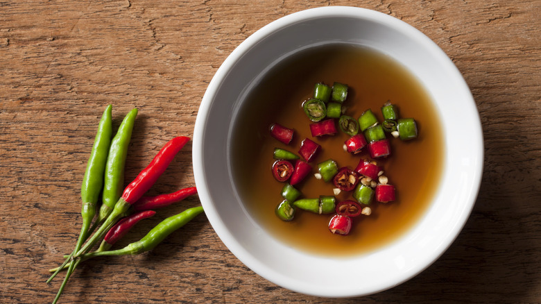 White bowl of fish sauce with Thai chili peppers