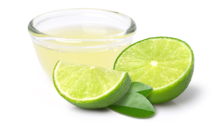 Limes and lime juice on white background