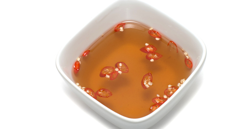 Fish sauce with chilies in white bowl on white background