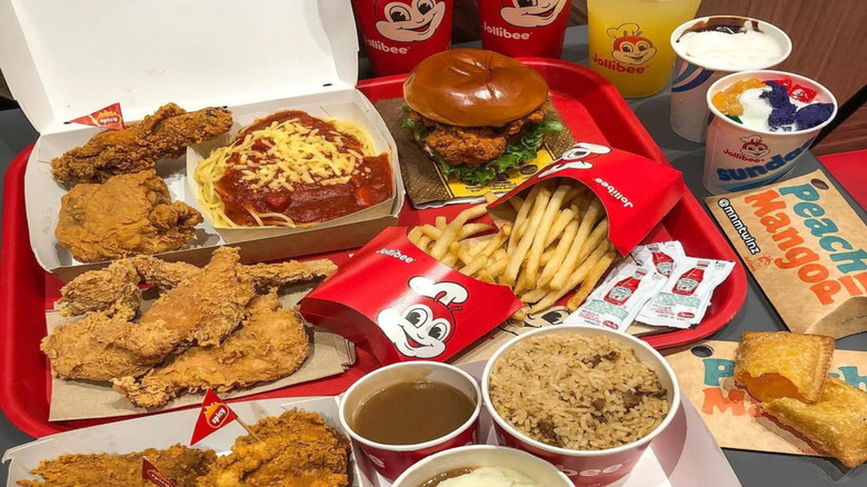 Jollibee meal deal with chicken, fries, mashed potatoes, and drinks on white background