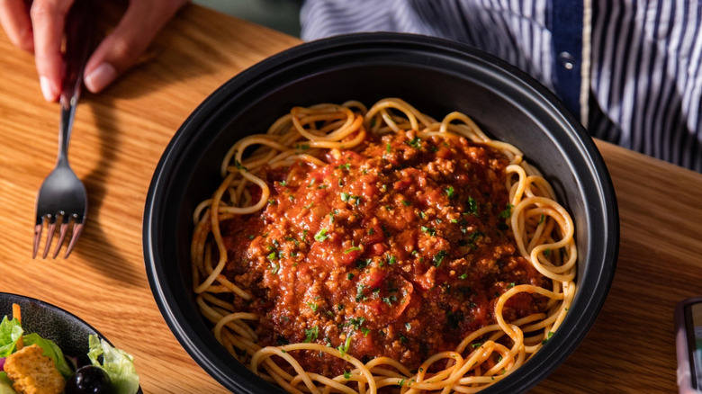Leftovers from Olive Garden on wooden table with person holding fork