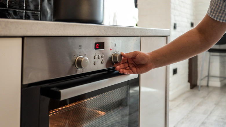 Hand adjusting temperature on oven door