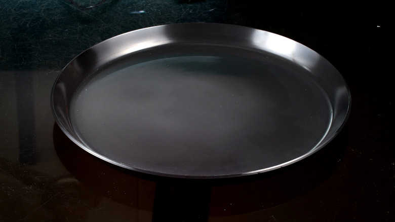 Black aluminum pizza pan on black background