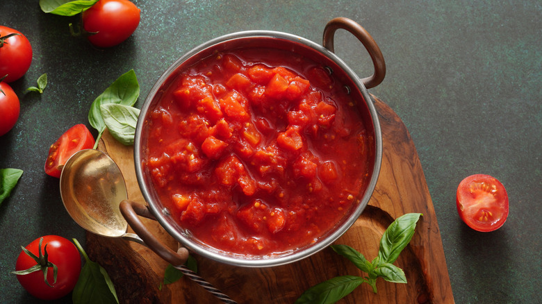 Homemade tomato sauce in pot surrounded by ingredients