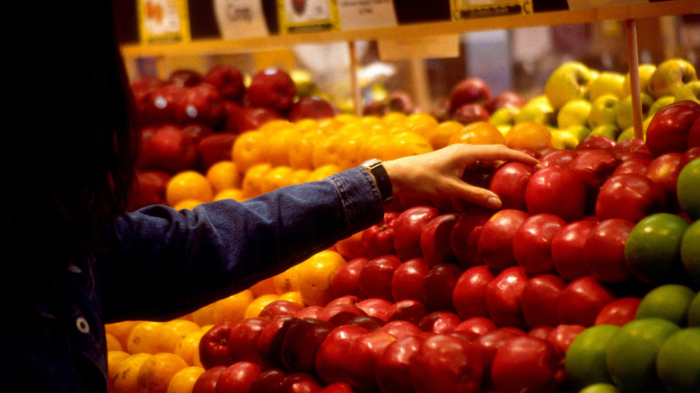 Hand picking apple from grocery store display