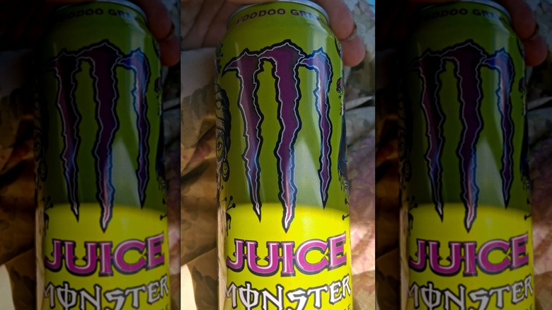 Hand holding can of Monster Energy Juice Monster Voodoo Grape