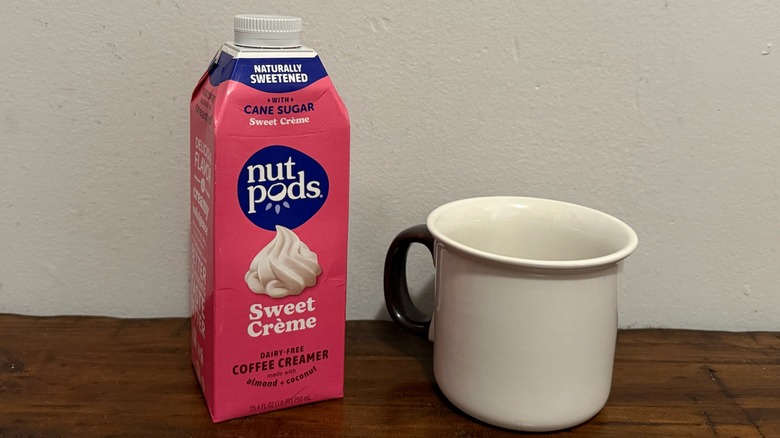 container of Nutpods sweet cream creamer next to a cup of coffee