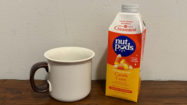 container of Nutpods candy corn creamer next to a cup of coffee