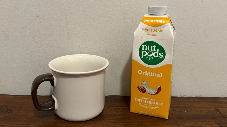 container of Nutpods original creamer next to a cup of coffee