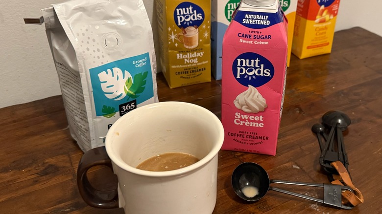 bottles of coffee creamer, a bag of coffee beans, a cup of coffee, and measuring spoons