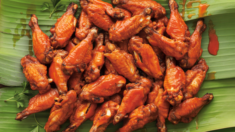 Large pile of chicken wings on big green leaf