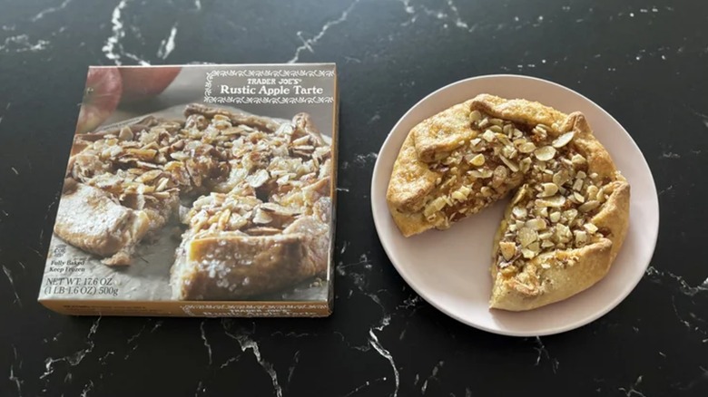 A Trader Joe's apple tart next to its box on a black marble counter