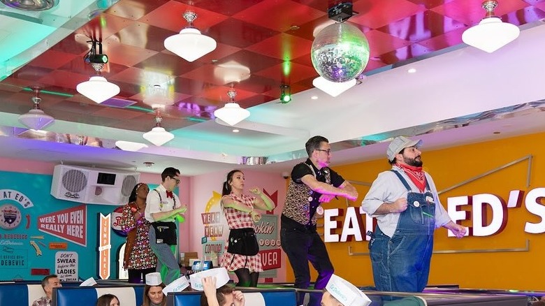 Waitstaff dancing on tables in a restaurant