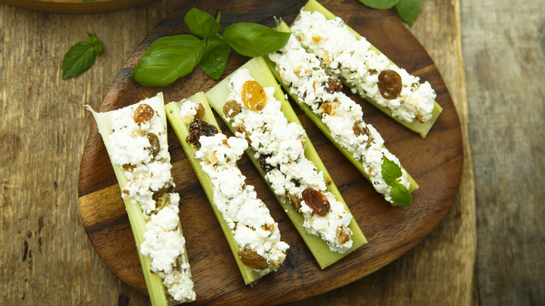 a wooden plate with five stuffed celery pieces