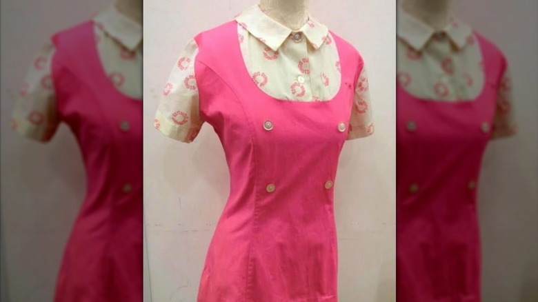 A pink Dunkin' uniform with buttons and a shirt