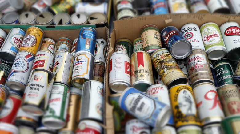 A pile of vintage beer cans in a box at a flea market.