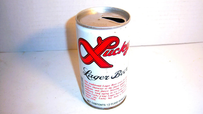 Vintage flat top can of Lucky Lager, opened and sitting against white background.