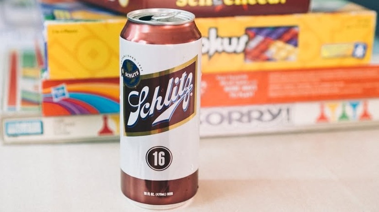 Open can of Schlitz beer in front of stack of board games.