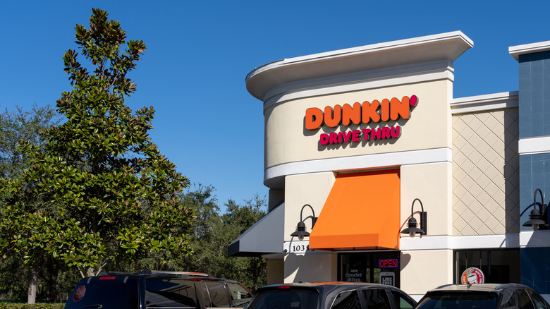 Dunkin' storefront with view of sky and tree