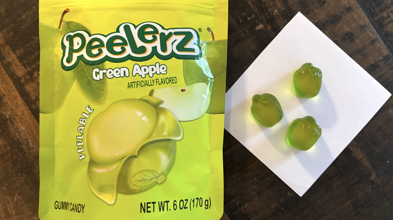 Peelerz green apple flavored gummy candy in bag and paper on wooden table.