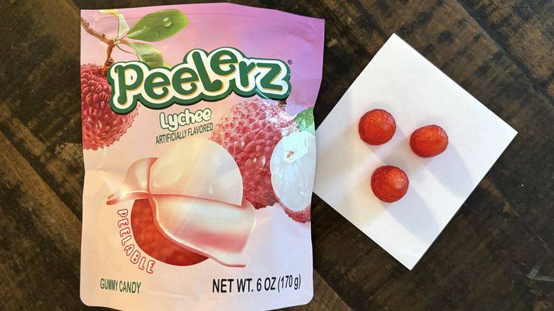 Peelerz lychee flavored gummy candy in bag and paper on wooden table.