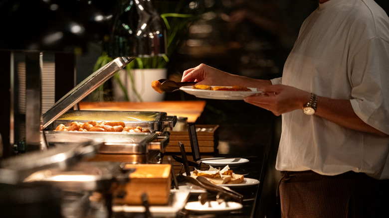a man taking food from a buffet table