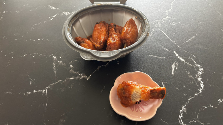 Pizza Hut Buffalo medium wings in a container with one wing on the side on a plate