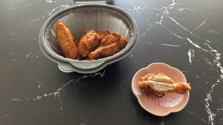 Pizza Hut garlic Parmesan wings in a plastic bowl next to one wing on a separate plate