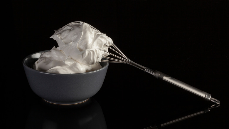 Grey ceramic bowl contained whipped cream against a black background