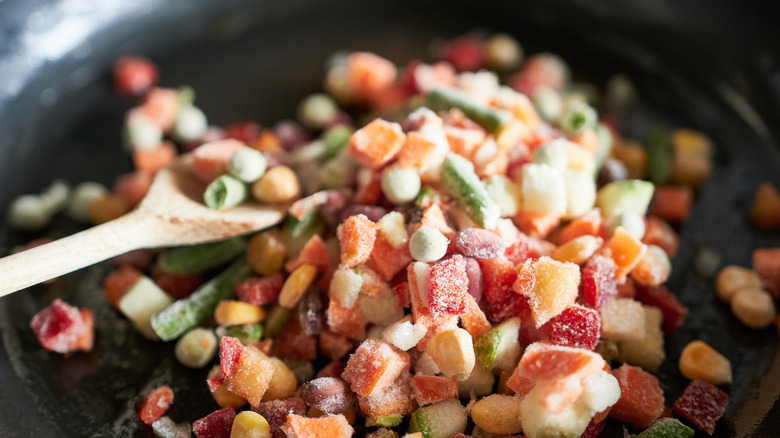 Frozen vegetables in skillet with wooden spoon