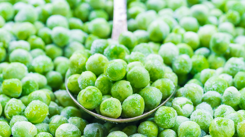 Close up of pile of frozen peas with spoon