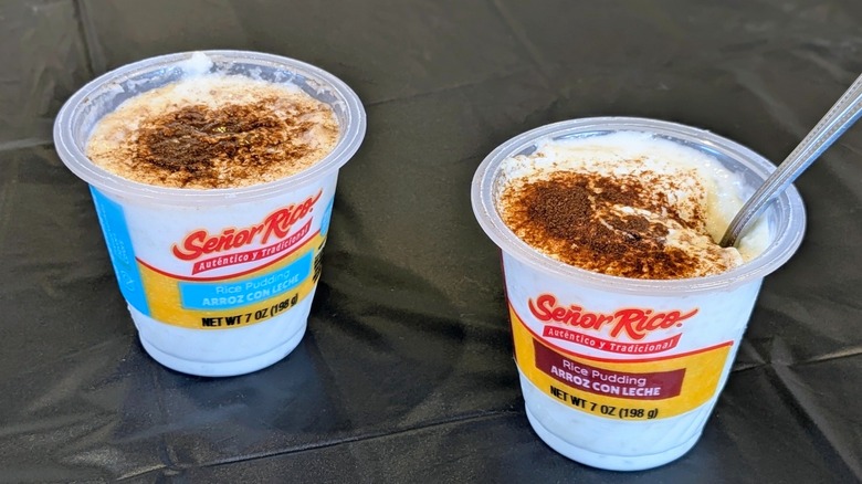 Two plastic cups of Señor Rico rice pudding, one with a spoon in it, on a black tablecloth