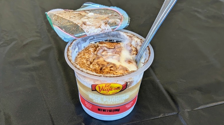 An open plastic container of El Viajero rice pudding with a spoon in it