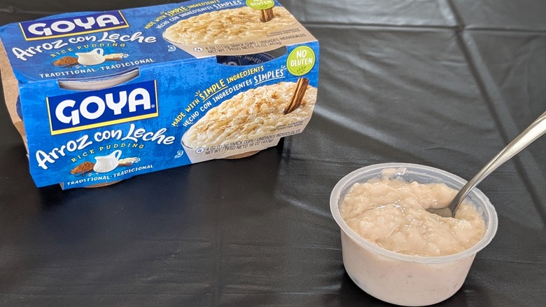 A paper package of Goya rice pudding cups next to an open cup with a spoon in it