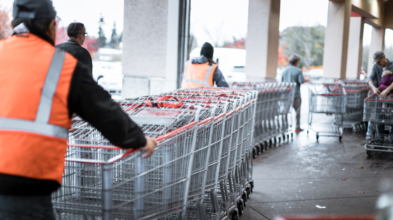 Costco employee pushing carts in parking lot