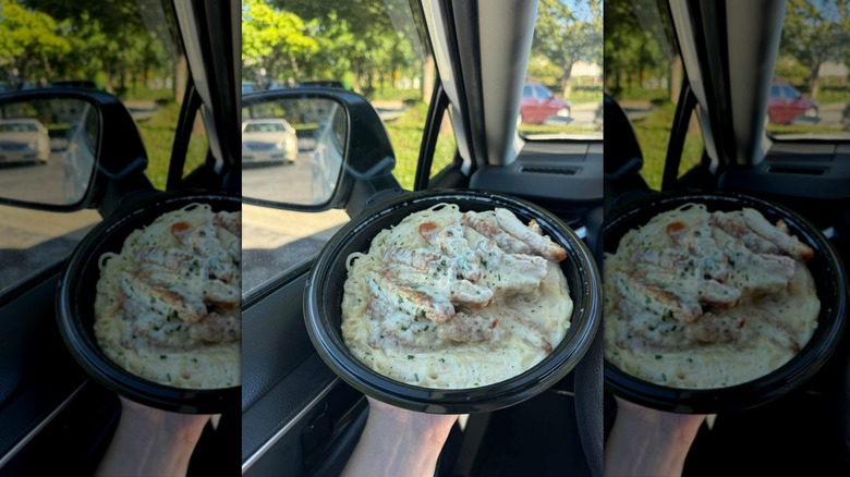 Hand holding container of chicken fettuccine from Olive Garden
