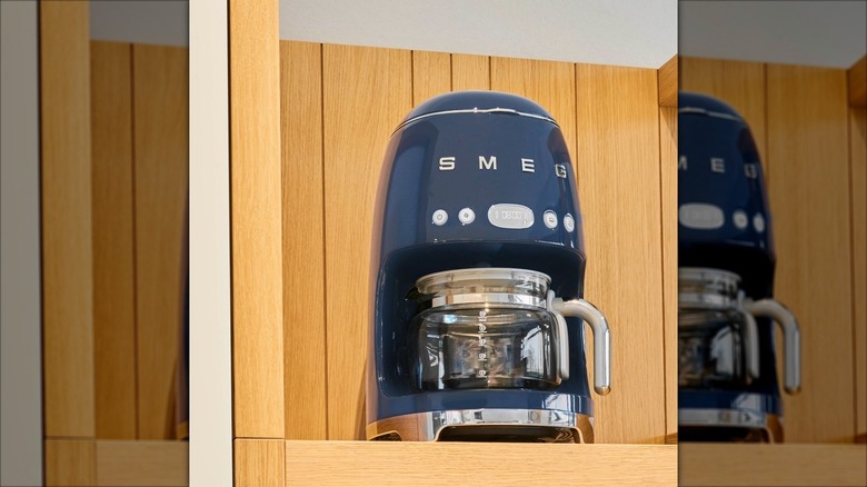 Navy blue Smeg drip coffee maker on wooden cupboard