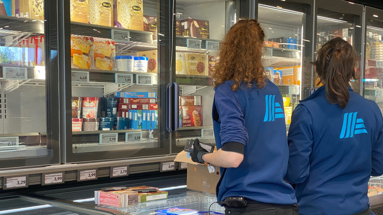 Two employees unloading stock in the frozen food aisle