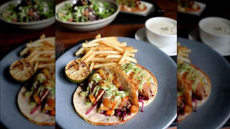 Fish tacos with french fries on a grey plate
