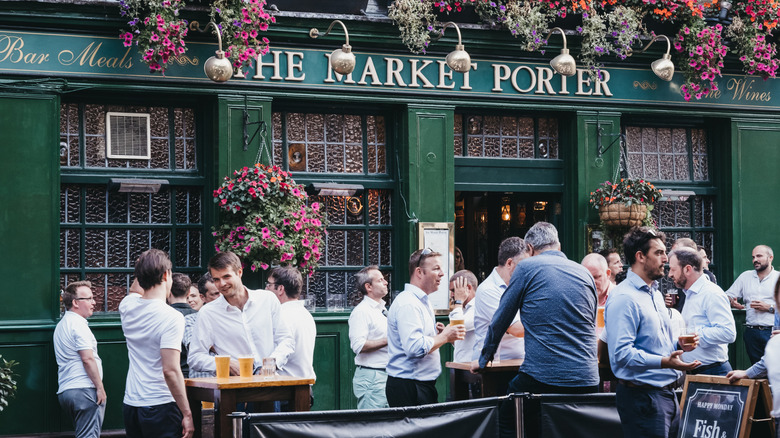 People standing and drinking outside The Market Porter English pub in Borough Market, one of the largest and oldest food markets in London.